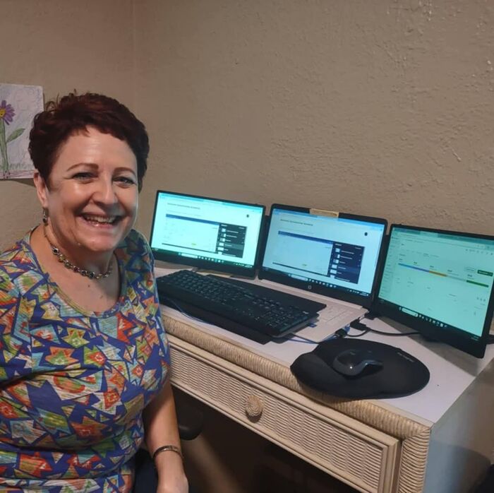 Shari Haley at her desk, working across three monitors
